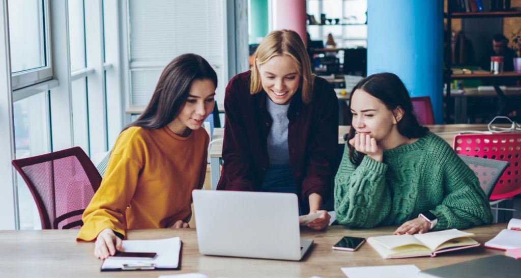 Three women talking in front of a computer